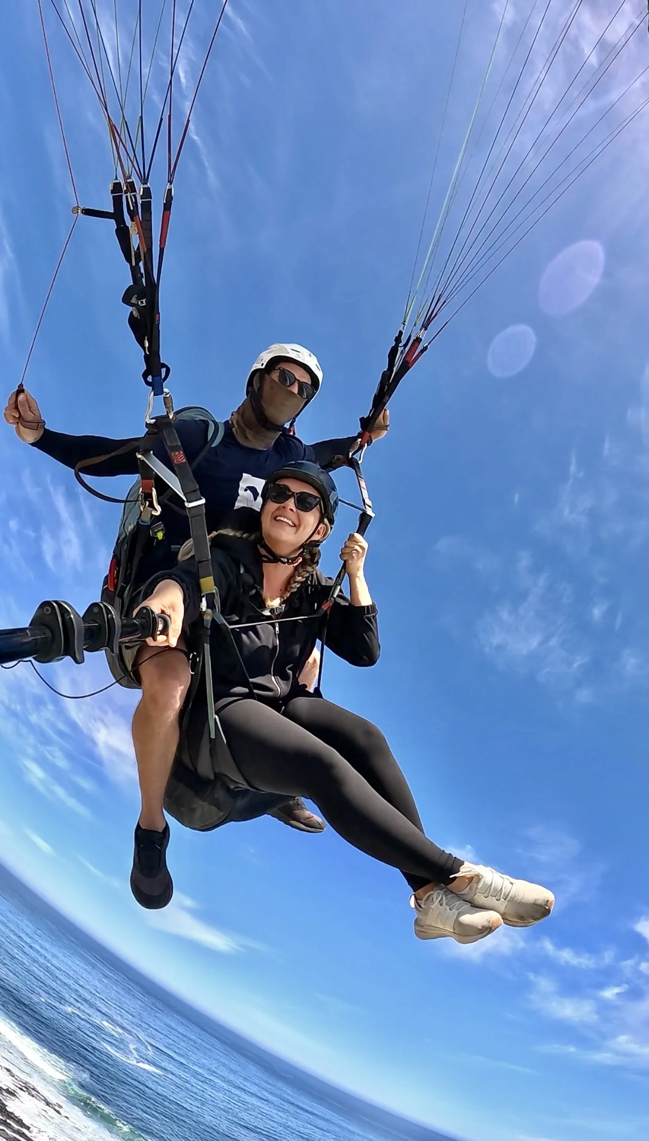 A girl smiling while tandem paragliding in Cape Town, South Africa from Signal Hill