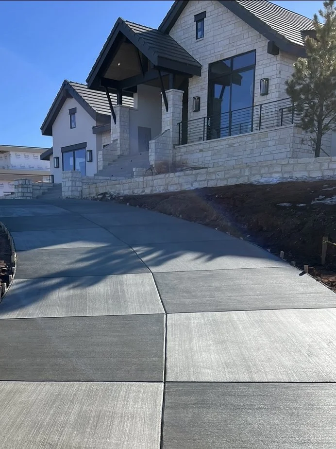 Newly constructed house with a sloped driveway and stone exterior walls.