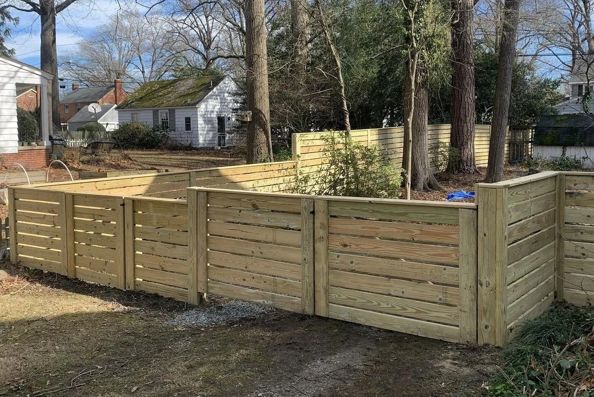 Newly built wooden privacy fence surrounding a backyard with trees and neighboring houses.