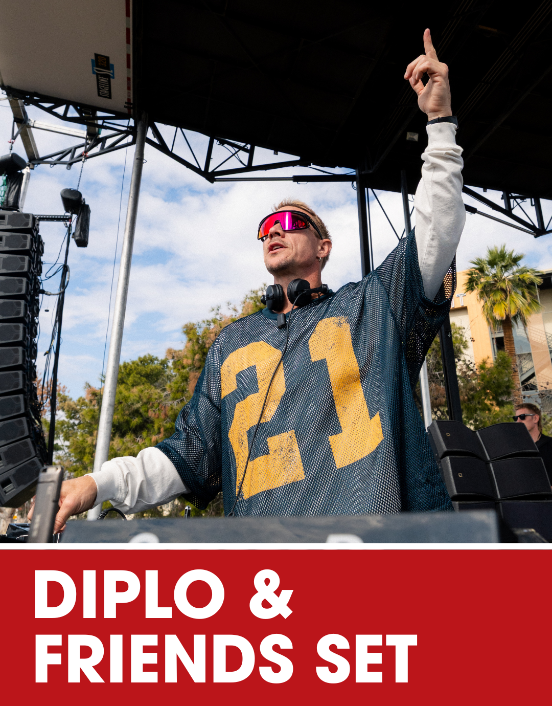 Overhead view of a DJ standing behind a set of four turntables and a mixer on a stage, with cables and personal items scattered around, during a live music event.