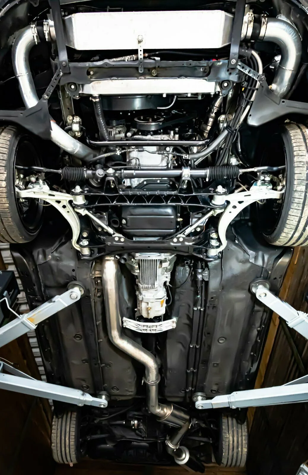 View of the underside of a car showing the suspension, exhaust system, and engine components.