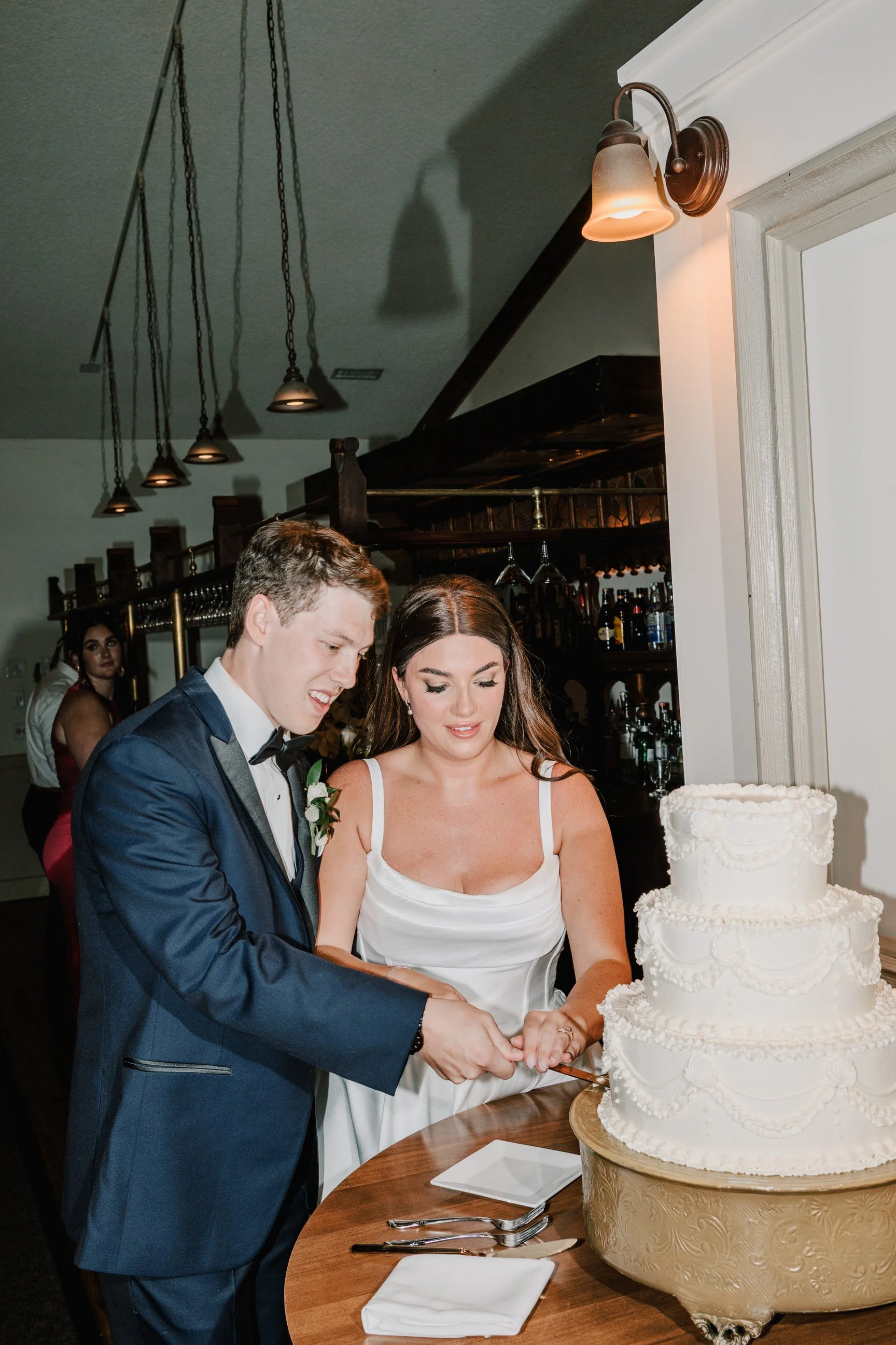 Bride and groom cutting a wedding cake together at their reception.