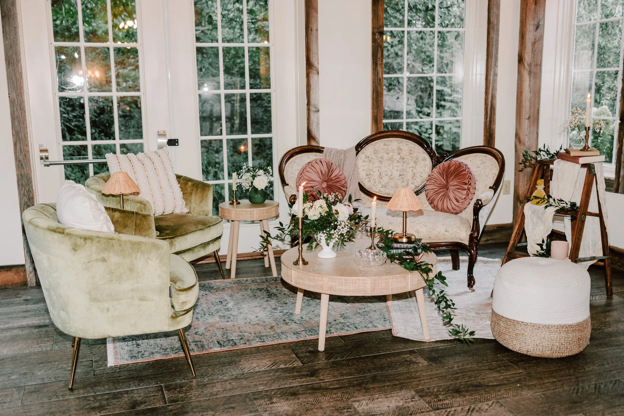Cozy living room with vintage and modern furniture, large windows, and floral decorations.