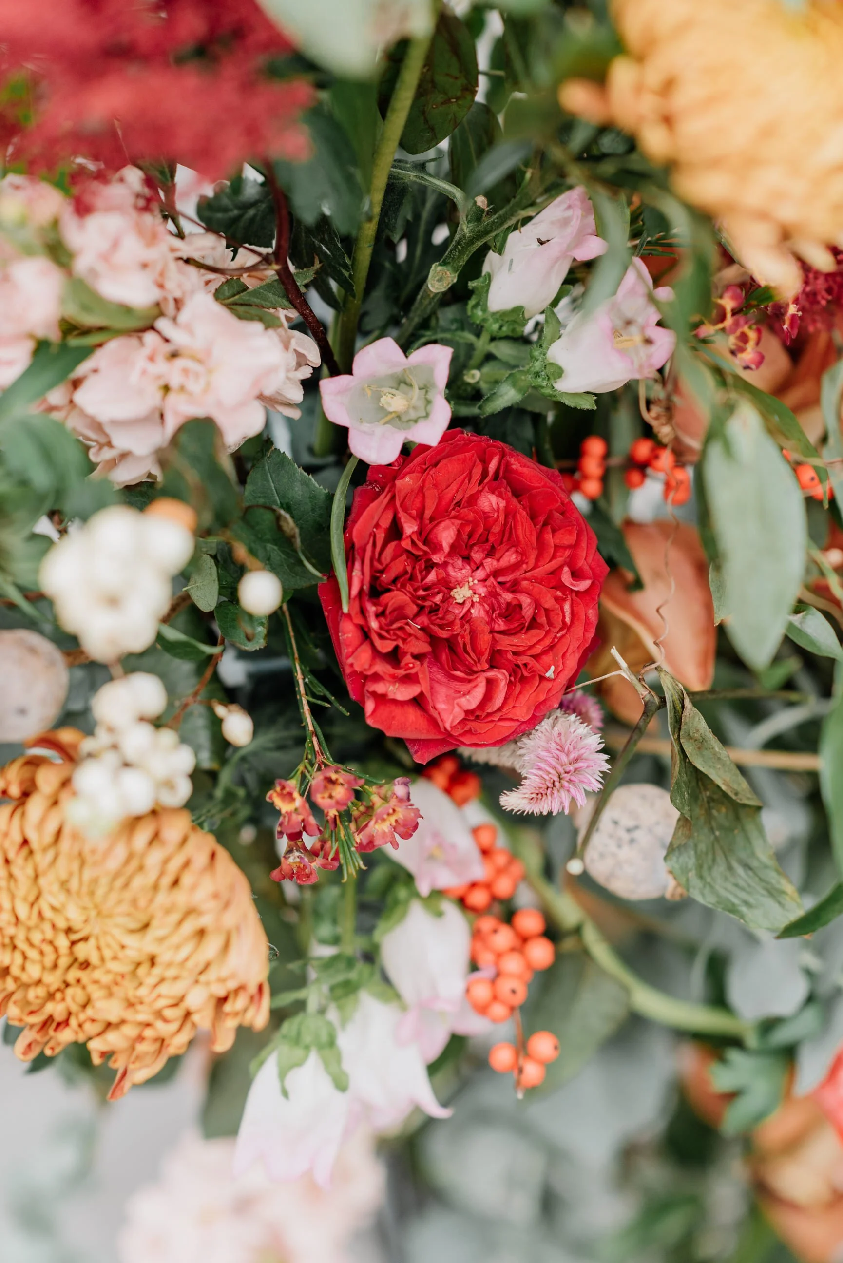 Close-up of a colorful flower arrangement with various pink, orange, yellow, and white flowers and green leaves.