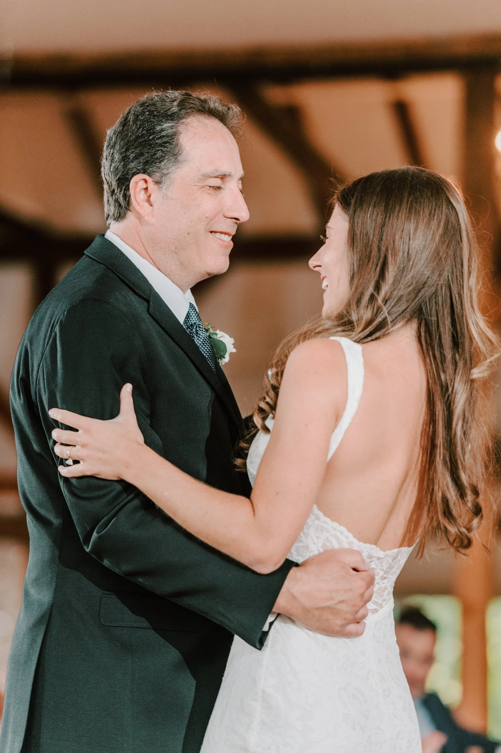 A bride and groom sharing a dance at their wedding reception, looking at each other and smiling.