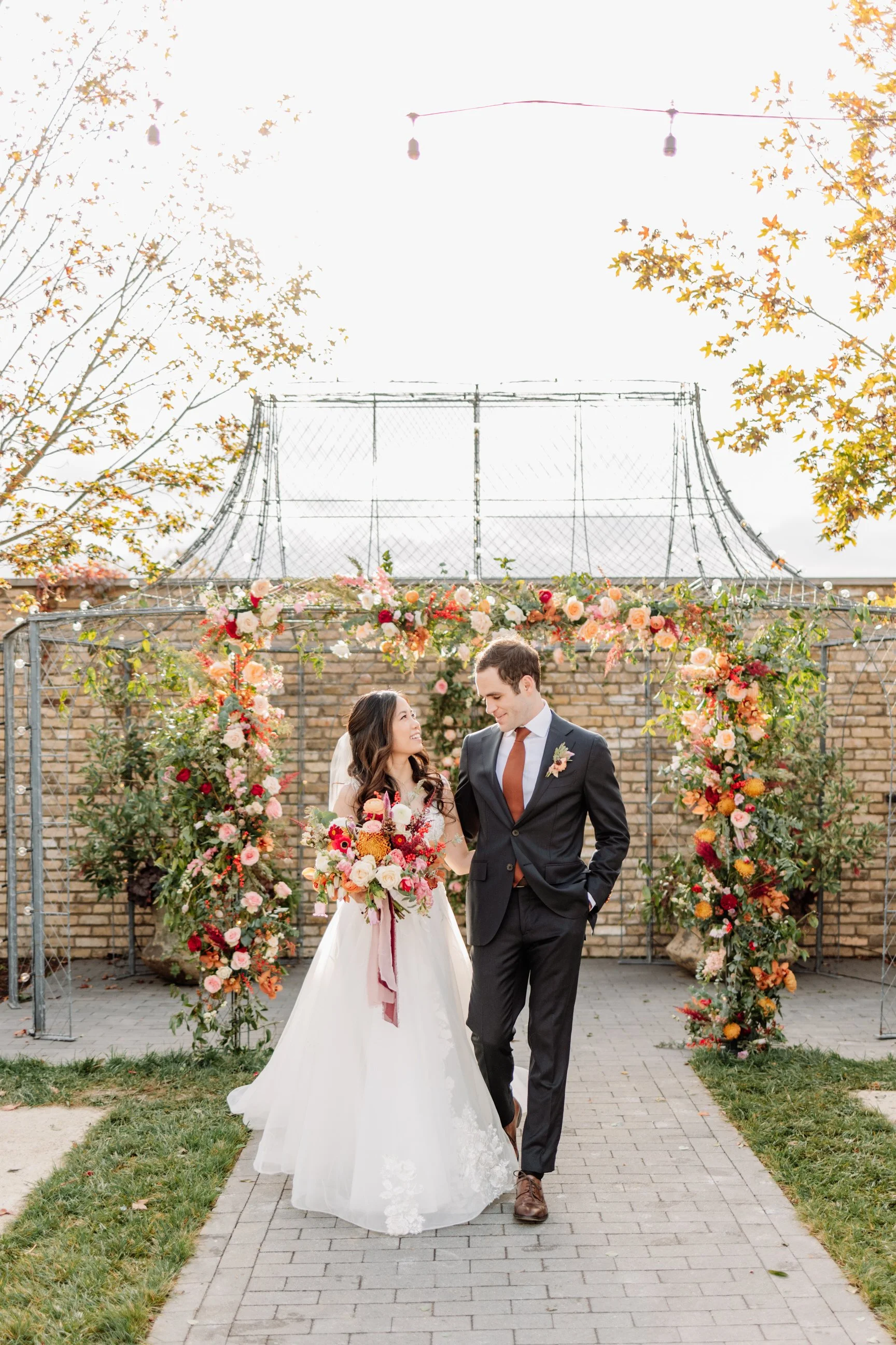A bride and groom walking under a floral arch at their wedding outdoor ceremony.