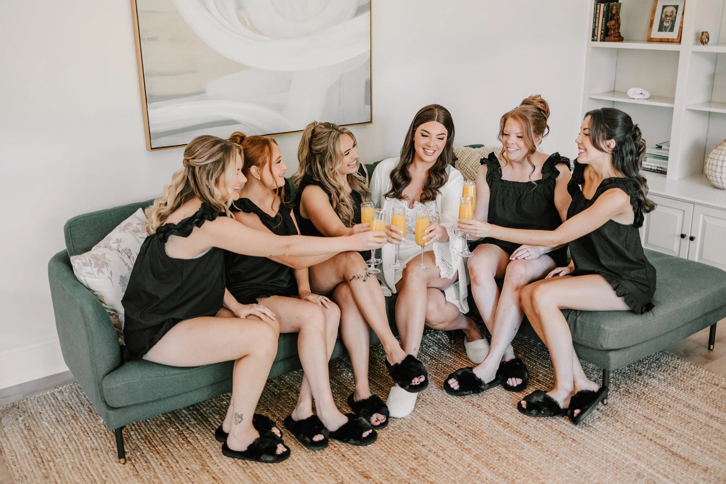 A group of women celebrating with drinks on a couch in a living room.