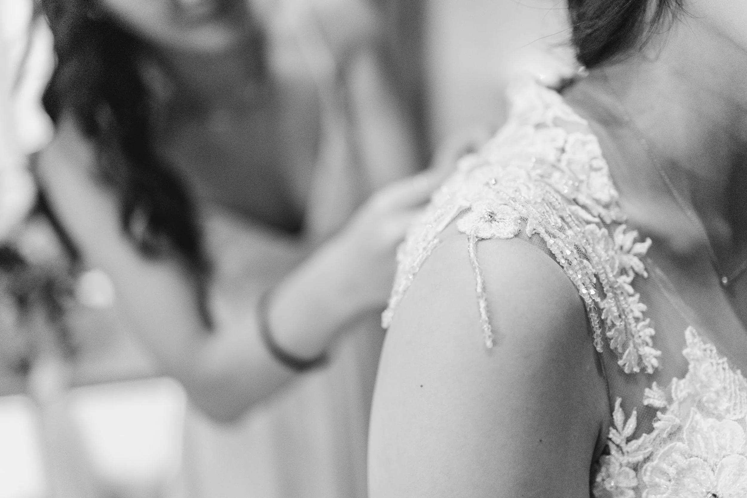 Close-up of a woman wearing a lace dress on her shoulder, blurred background.