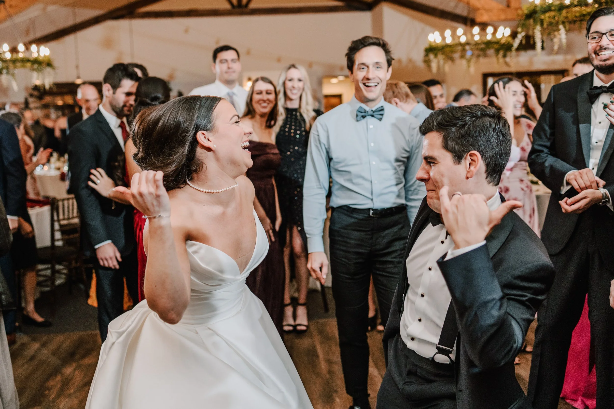 A bride and groom dancing and celebrating at their wedding reception, surrounded by guests.