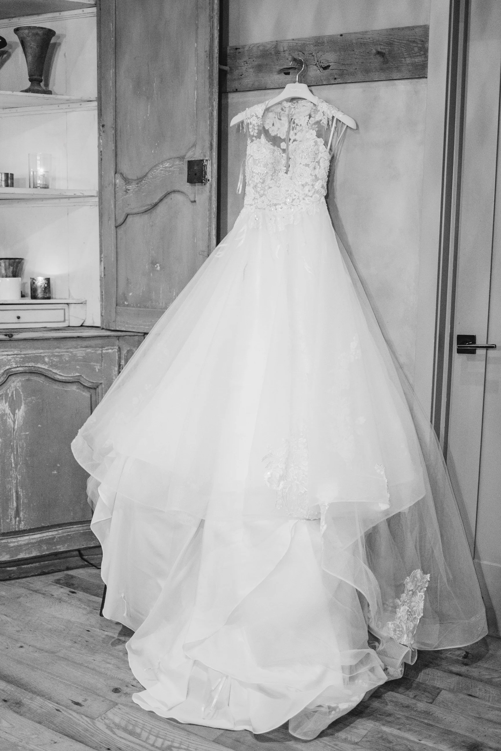 A wedding dress hanging on a hanger in a room with wooden floors and rustic furniture.