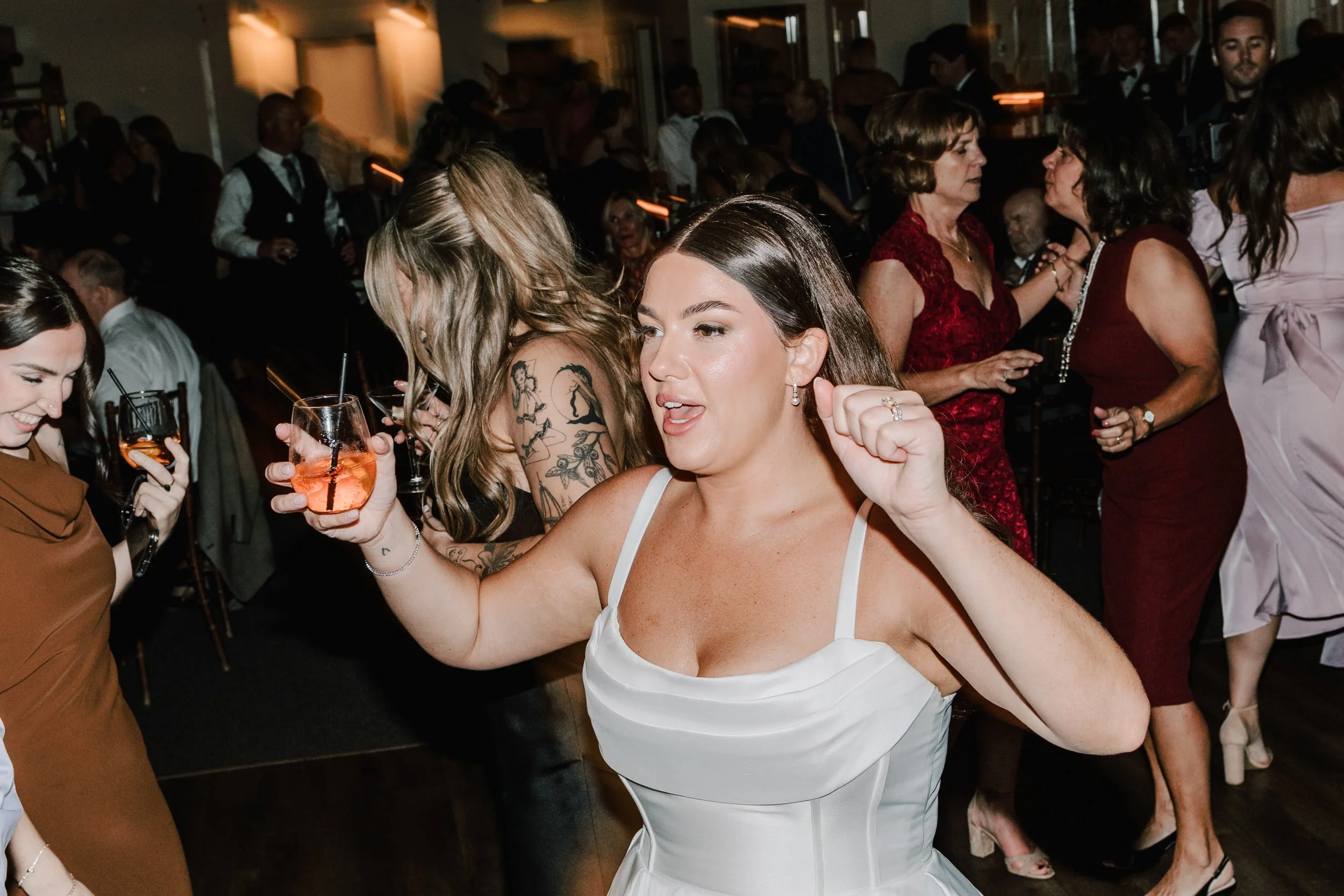 People dancing and enjoying drinks at a celebration or party in a lively indoor setting.