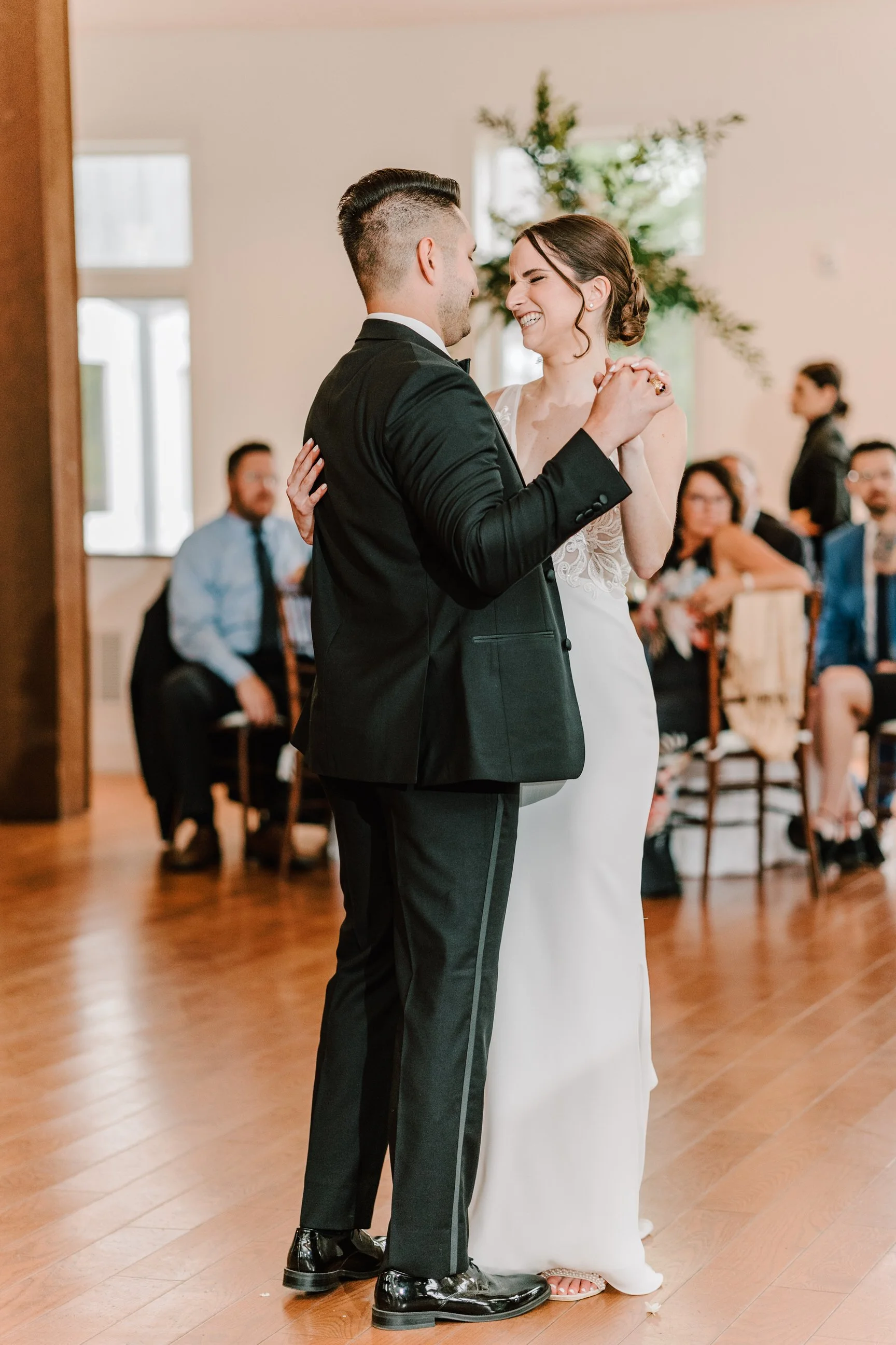 Couple having their first dance at a wedding reception, surrounded by seated guests. Philadelphia wedding photographer