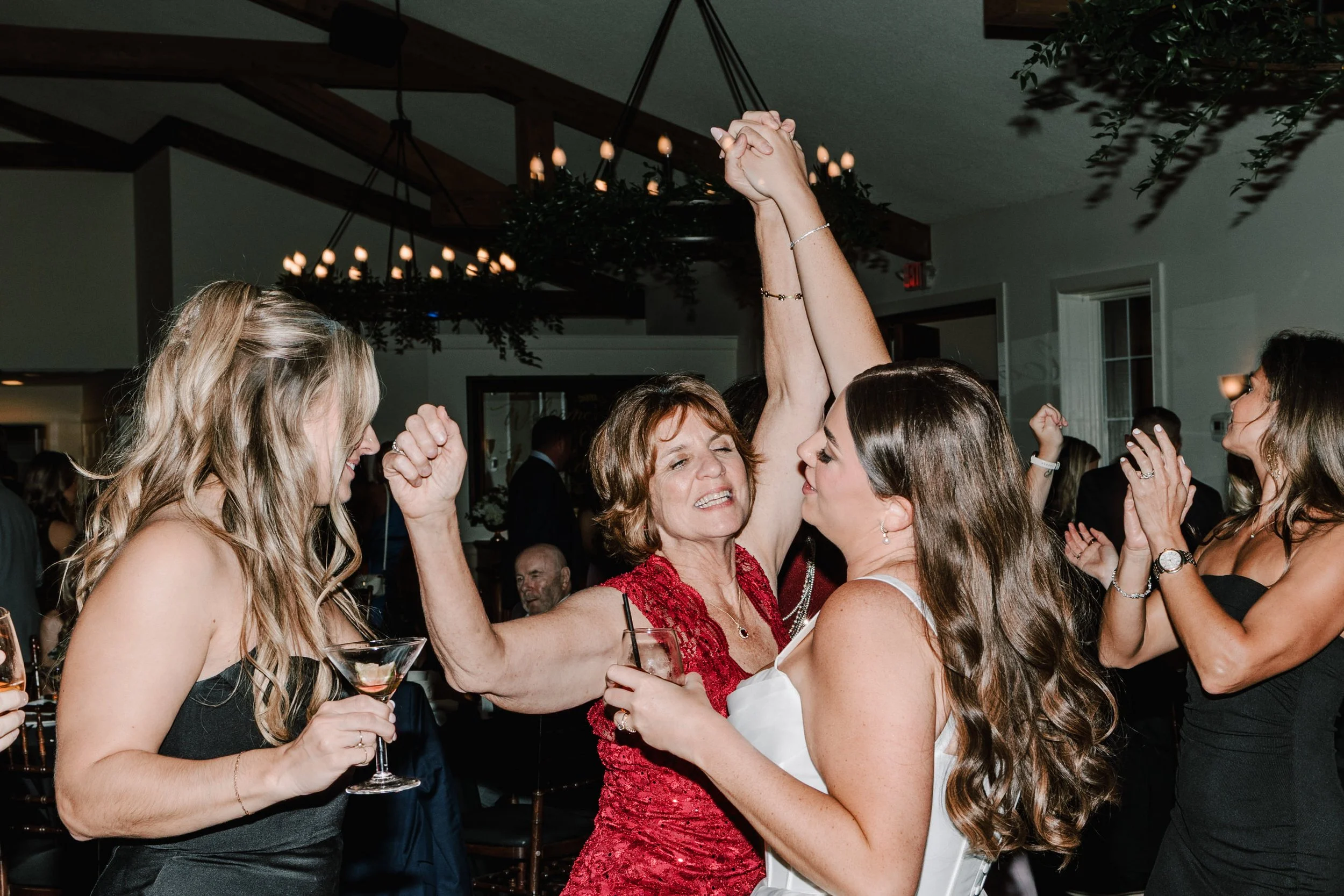 Women celebrating at a wedding reception, dancing and raising hands in victory