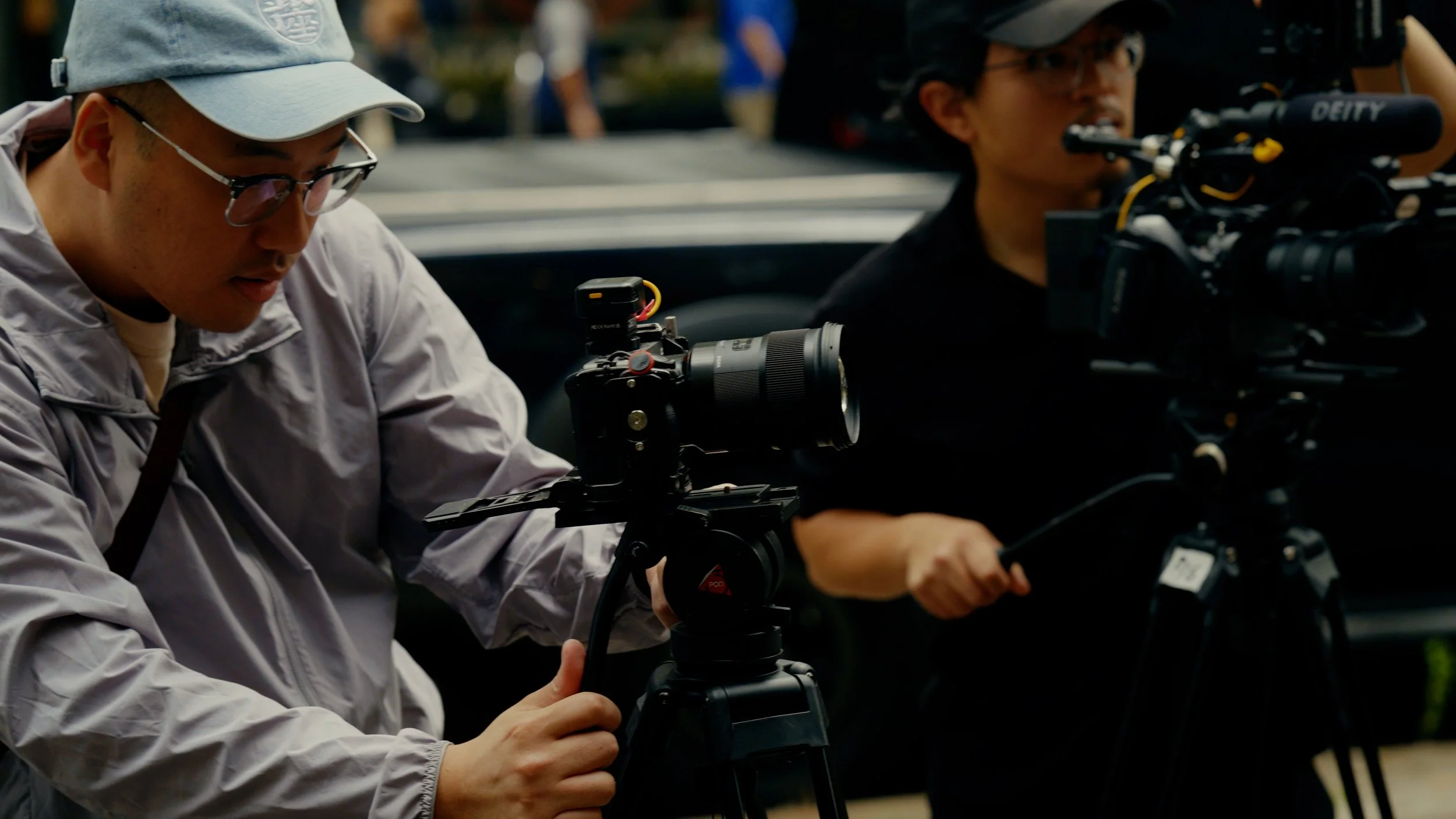 Two filmmakers operating professional video camera equipment outdoors.
