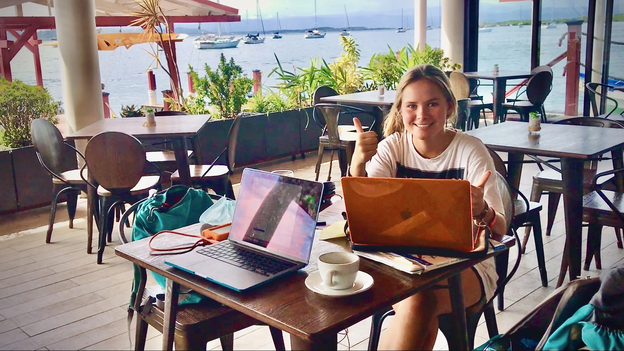 Girl - Rowan from S/V Mothership - sat at her laptop doing homeschooling in a cafe in Bocos Del Toro
