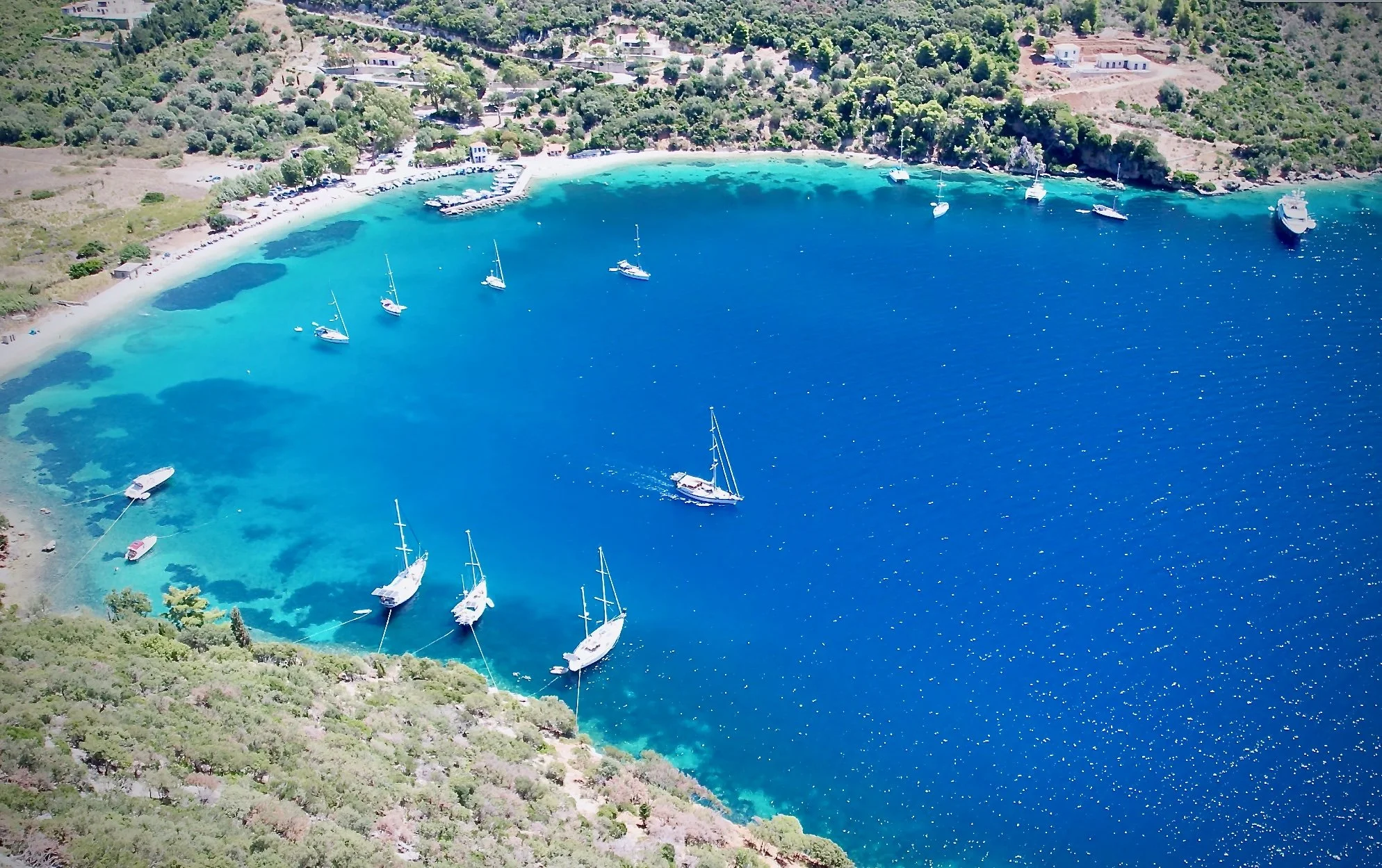 Aerial shot of a coastal bay with sailboats - S/V Mothership and others - at anchor or tied with shorelines