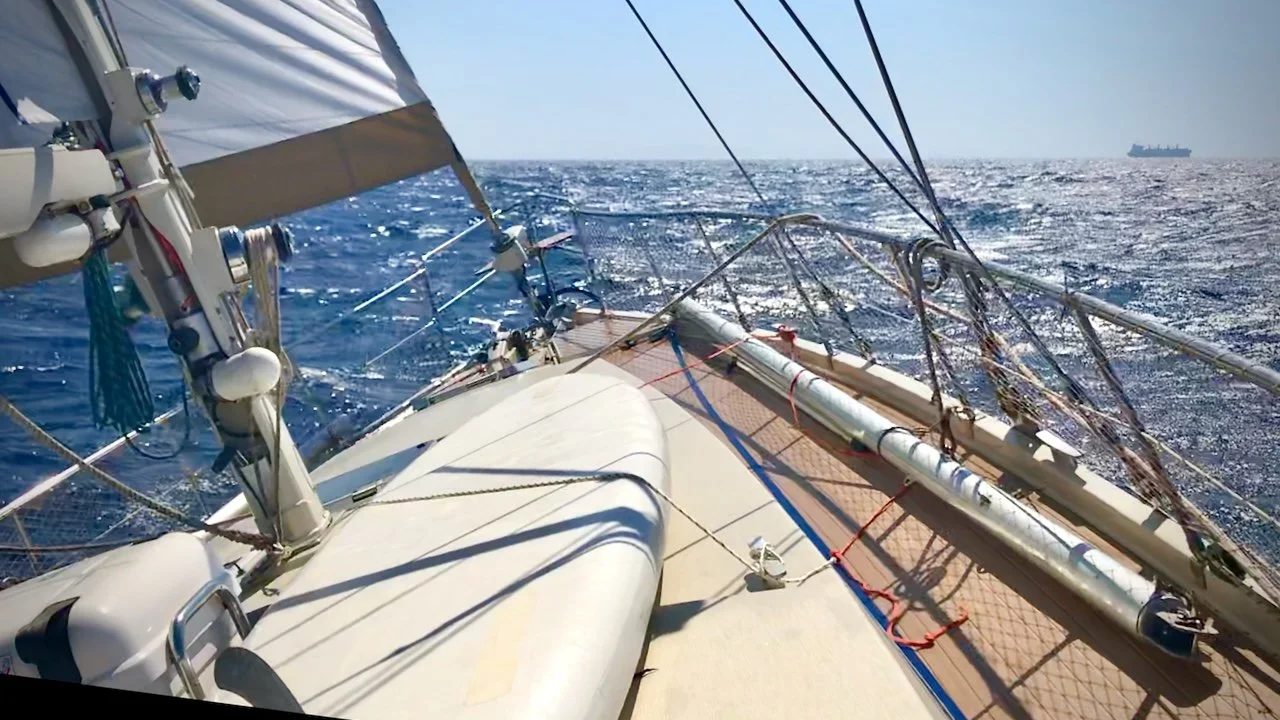 View from the fordeck of a sailboat - S/V Motherhsip - with a cargo ship seen on the horizon