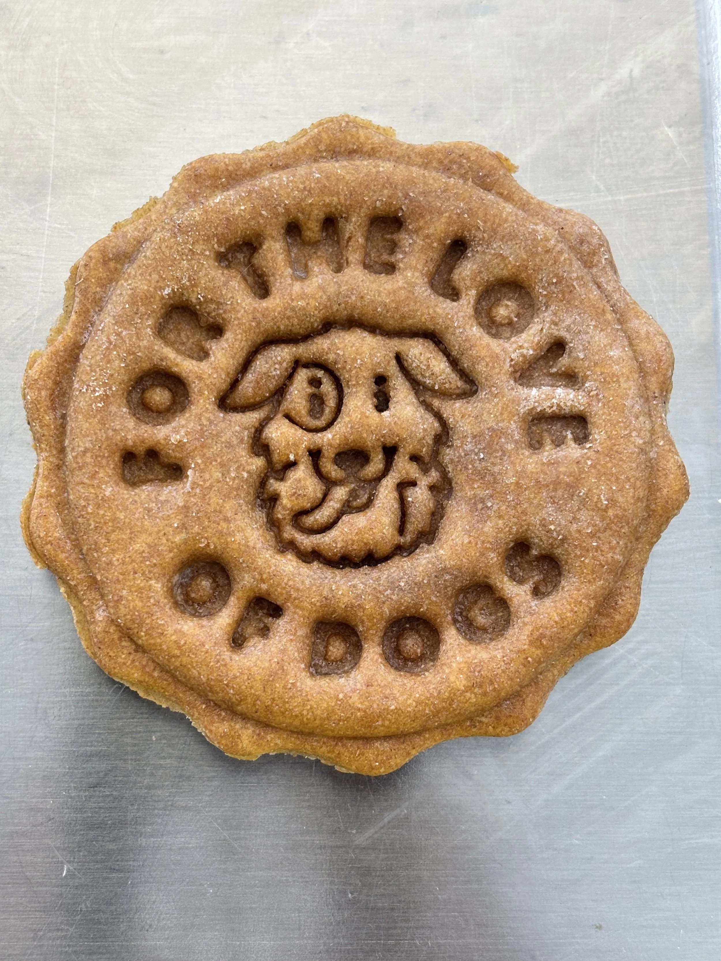 Close-up of a round cookie with the Emblem of Oscar the Grouch from Sesame Street and the phrase "Boy the Lo 2" around the edges.