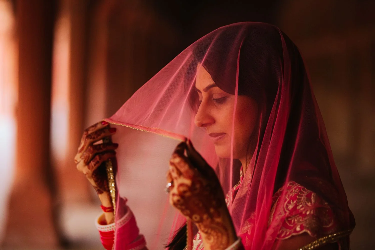 Indian bride seen through a vibrant red veil, exuding elegance in Taj Mahal, Agra India