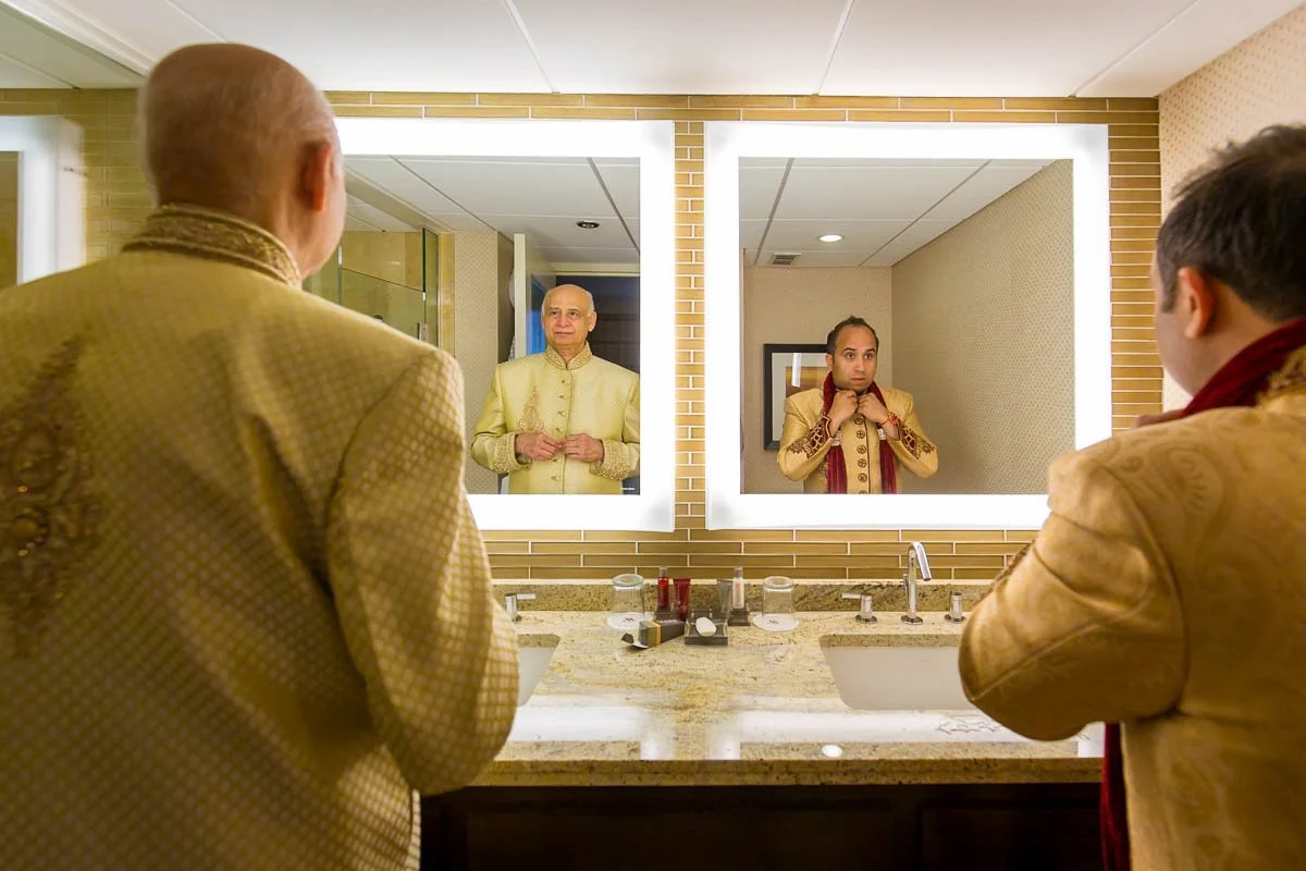 Groom and his father looking into mirror adjusting sherwanis getting ready for Indian wedding at Chicago Marriott O'Hare