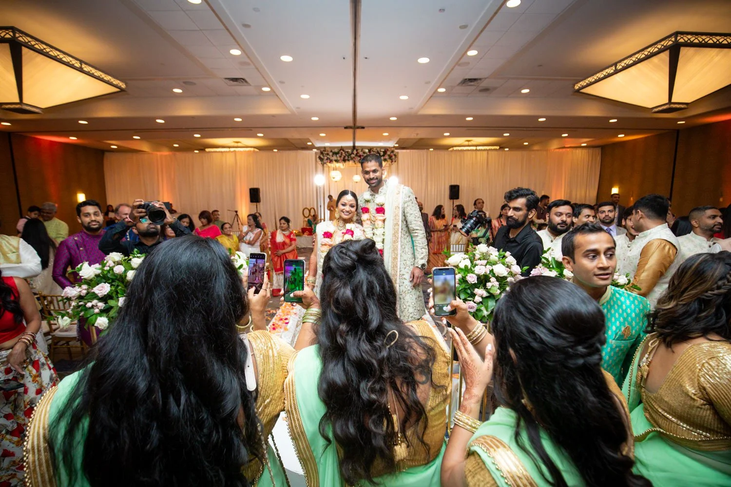Bridesmaids taking a picture of bride and groom as they leave the ceremony