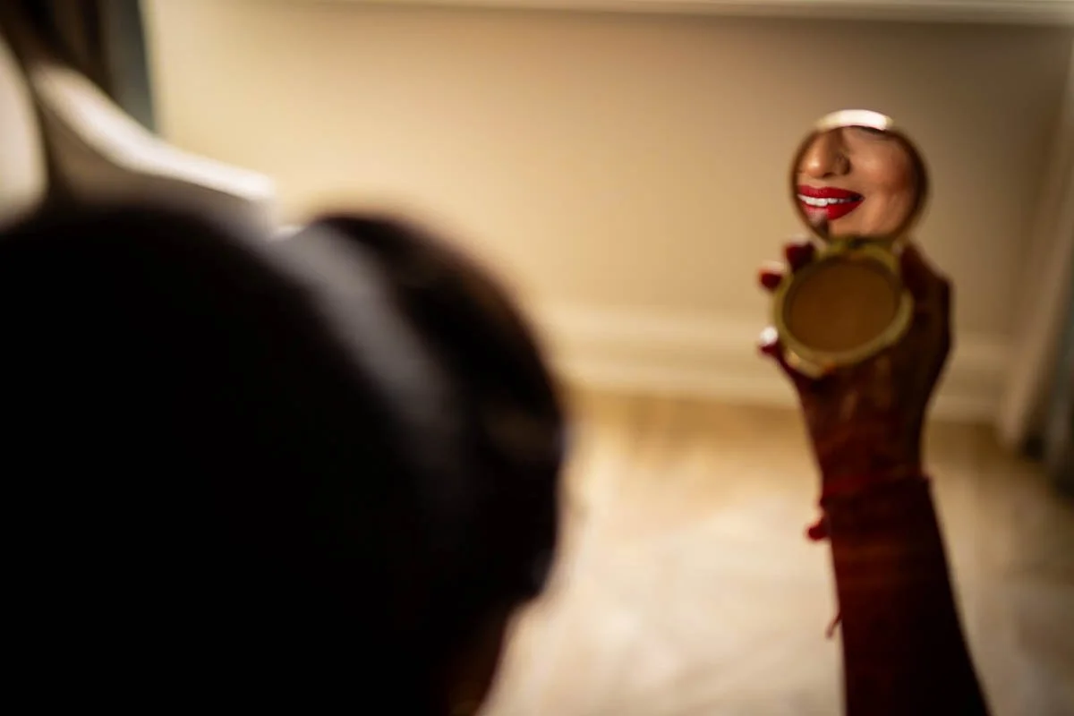 Bride lips reflection in makeup compact mirror while getting ready for Gujarati wedding at Ritz-Carlton Northern Virginia wedding