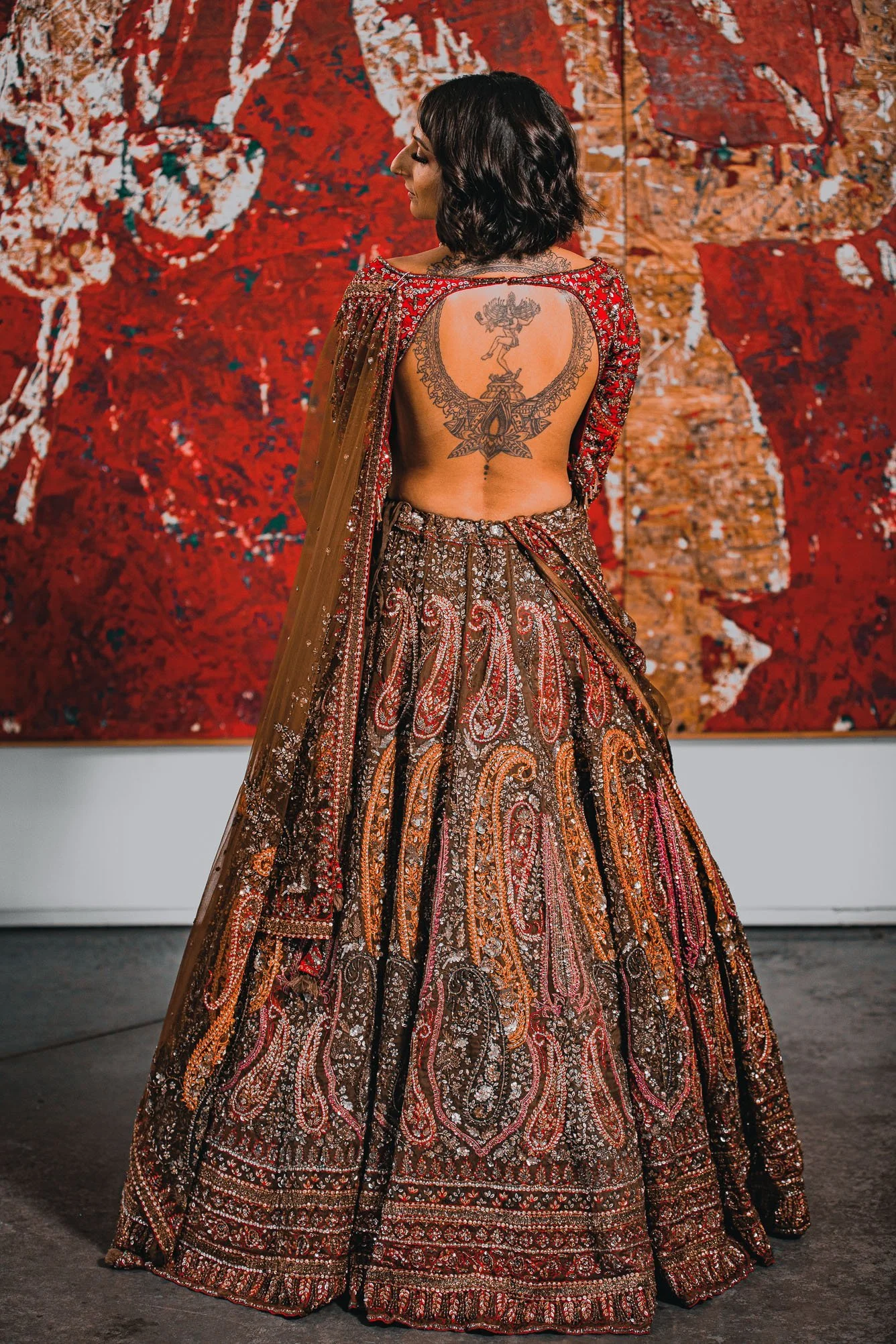 Khajana Boutique red lehenga modelled in front of artwork