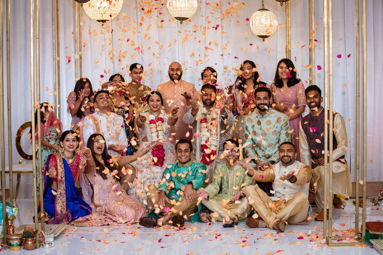 Family portrait throwing flowers in the air on the mandap at Hindu wedding ceremony