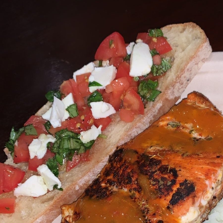 Burrata, cherry tomato and basil on sourdough bread, topped with salt and olive oil