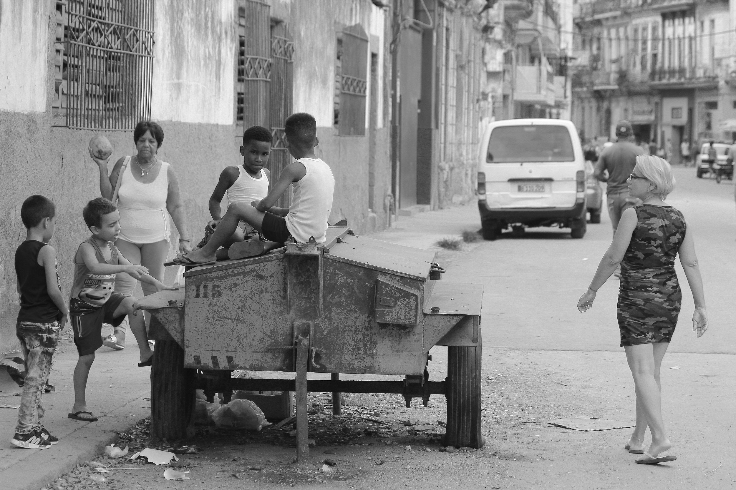Kids sit on a mobile toolbox while two women walk by them.| Credit: Reynaldo Cruz Diaz