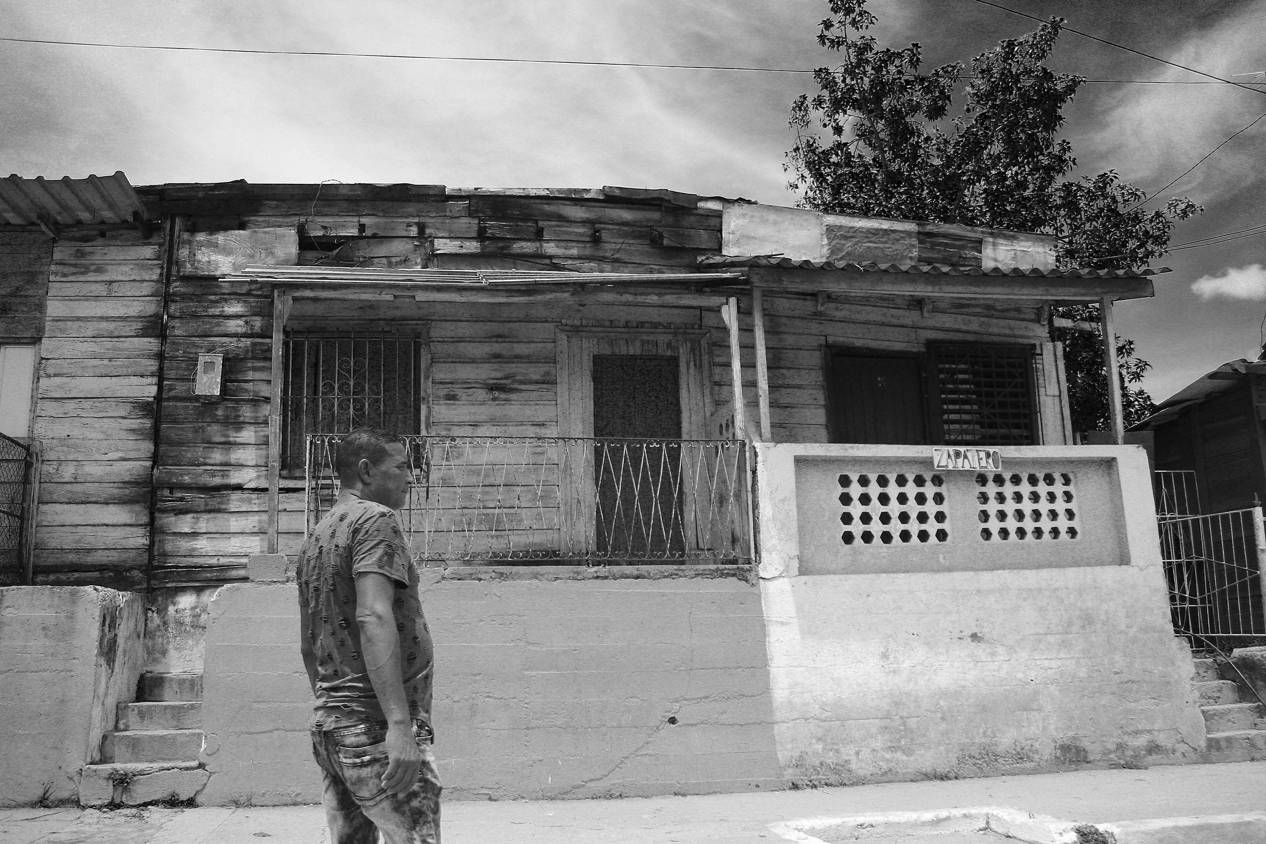A man stands in front of two dilapidated houses on the way to Finca Vigía , Ernest Hemingway’s house in Havana.| Credit: Reynaldo Cruz Diaz