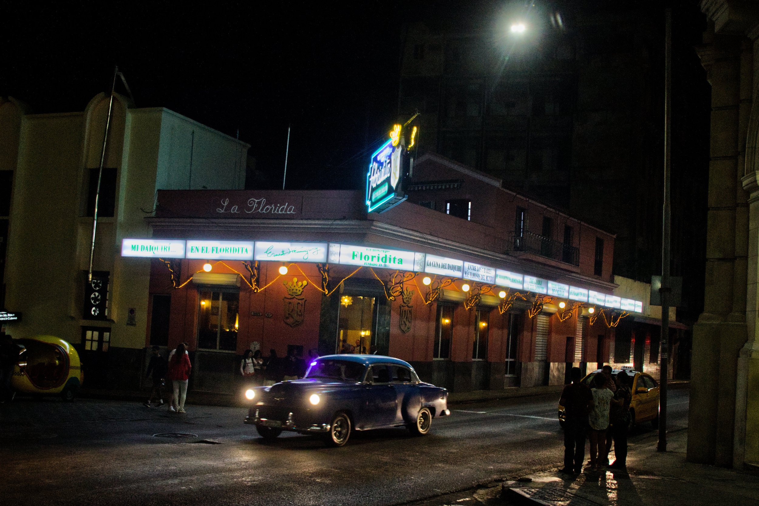 An old American car drives past the famous bar El Floridita, where Ernest Hemingway used to have his favorite Daiquirí.| Credit: Reynaldo Cruz Diaz