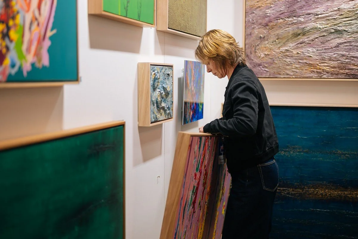 A woman looking at abstract paintings in an art gallery.