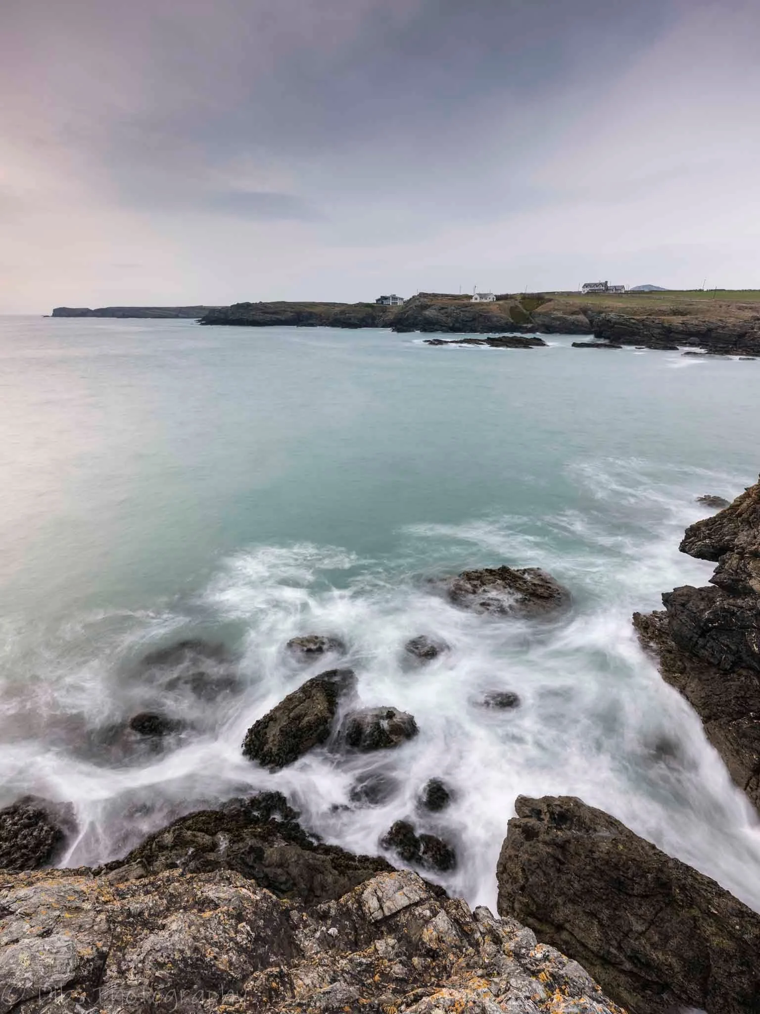 Long-exposure view of the rocky Anglesey coast and turquoise sea