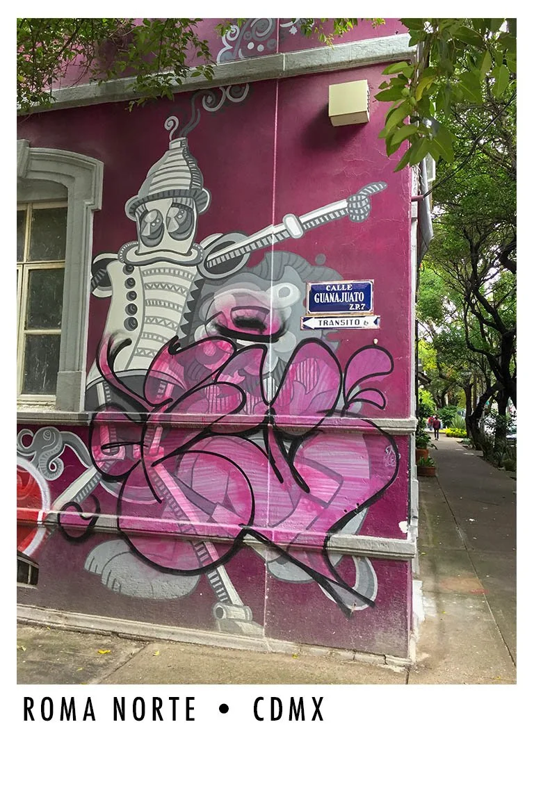 Street art mural on a pink wall featuring a robot playing a guitar and a bear's face. Street sign indicating Calle Guanajuato, CDMX, Mexico.