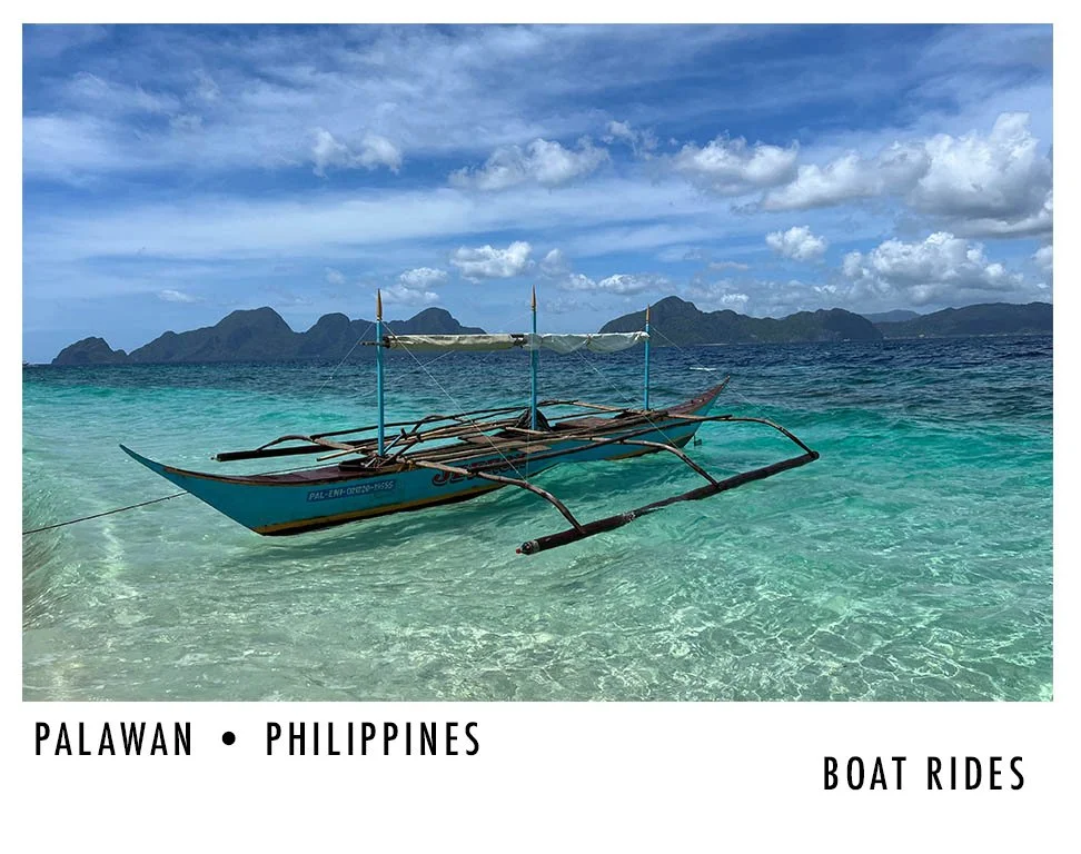 A traditional boat floating on clear turquoise water off the coast of Palawan, Philippines, with mountain islands in the background under a partly cloudy sky.