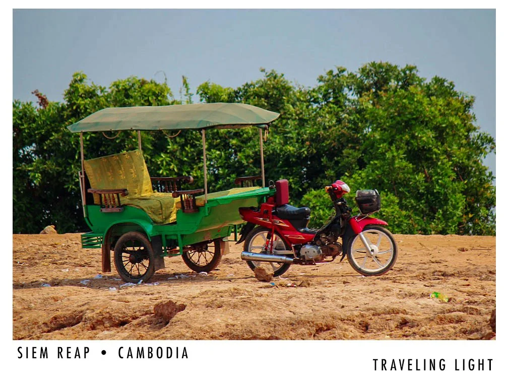 A red motorcycle with a sidecar on a dirt ground, with lush green trees in the background.