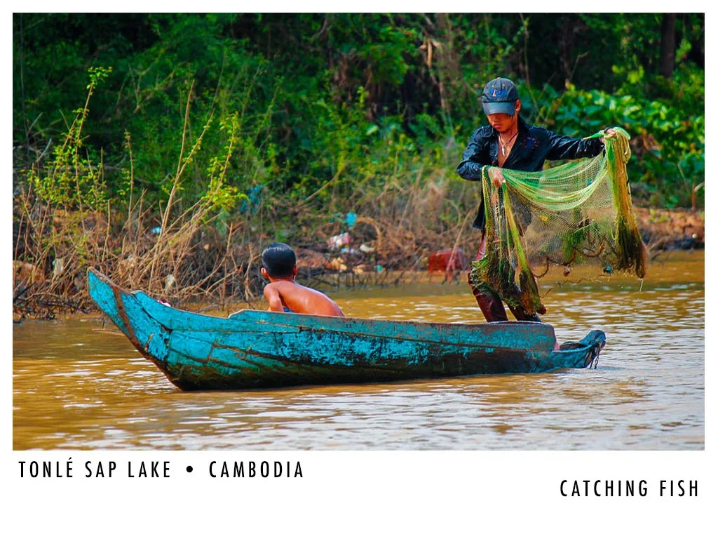 A person in a boat catching fish in Tonlé Sap Lake, Cambodia, with another person sitting in the boat.