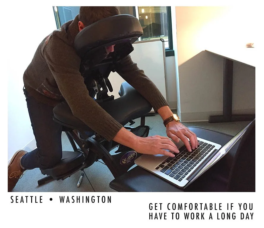 Person working on a laptop while seated in a specialized ergonomic standing desk chair in an office