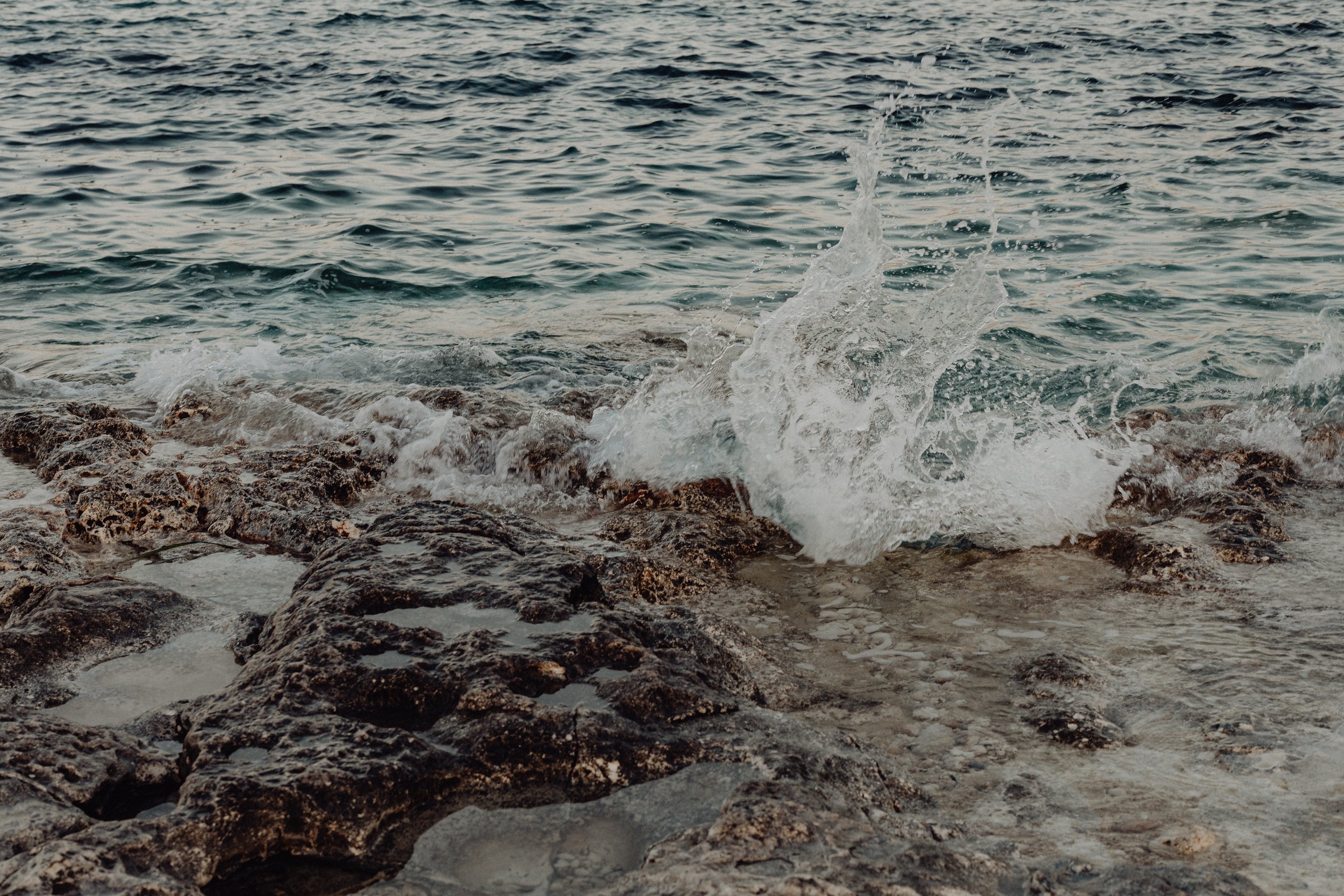 Waves crashing against rocks on the shoreline of the ocean.