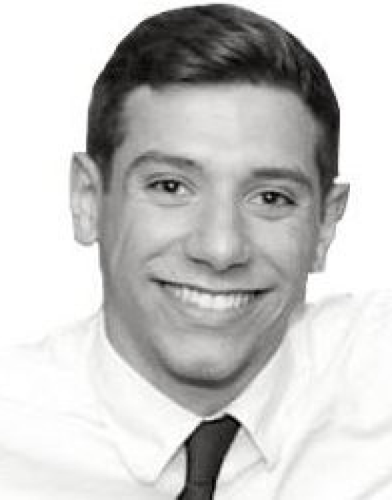 Black and white headshot of a young man smiling, wearing a white shirt and a dark tie.