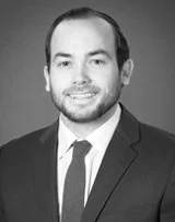 Black and white portrait of a man in a suit and tie, smiling.