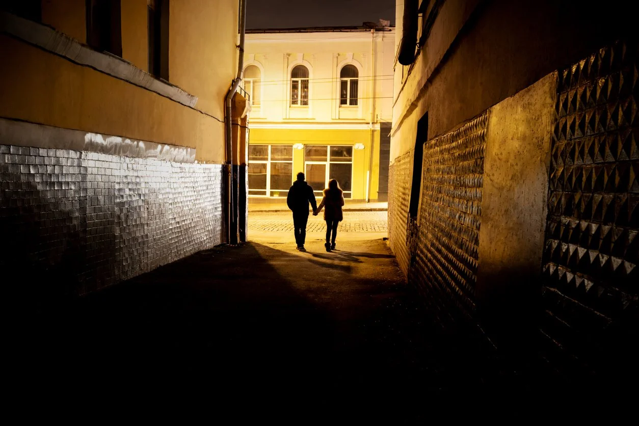 Husband and wife walking hand in hand through a tunnel toward daylight