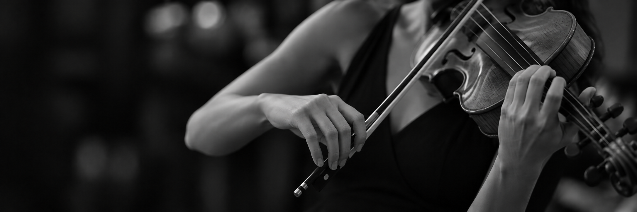 A person playing the violin in black and white, with focus on their hands and the instrument.
