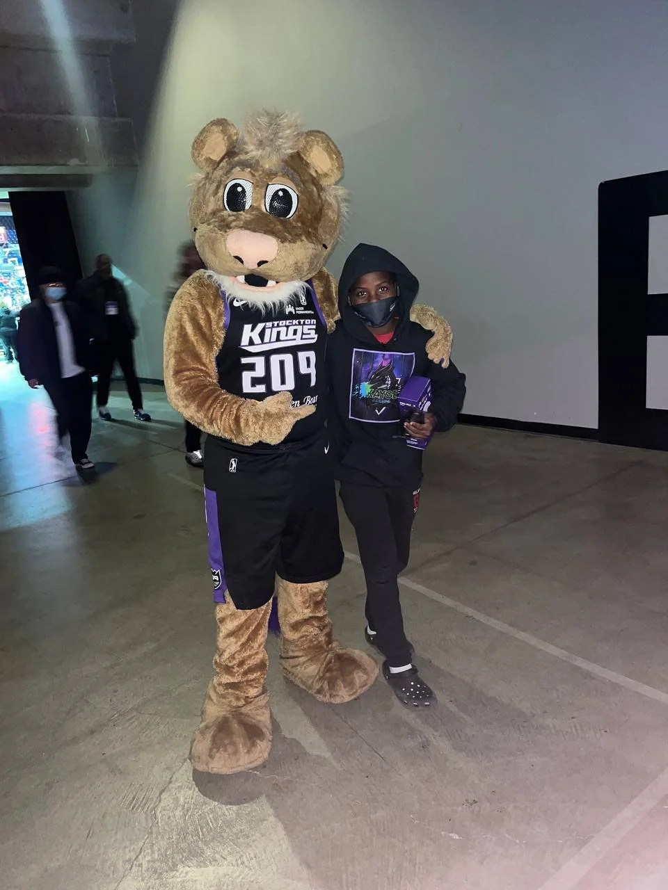 A lion mascot posing with a woman at an indoor event