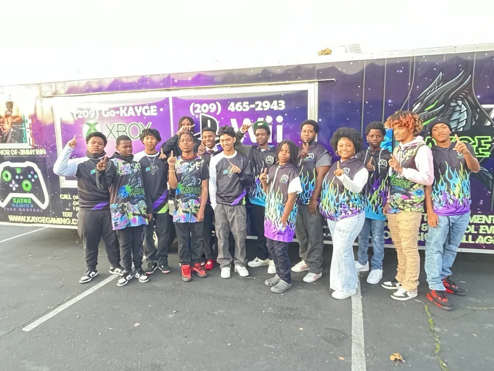 Young Gamer Tech participants in matching jerseys posing in front of a gaming truck