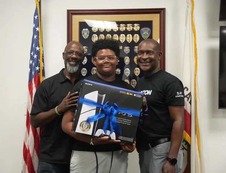 A young participant holding a PlayStation prize with two adults