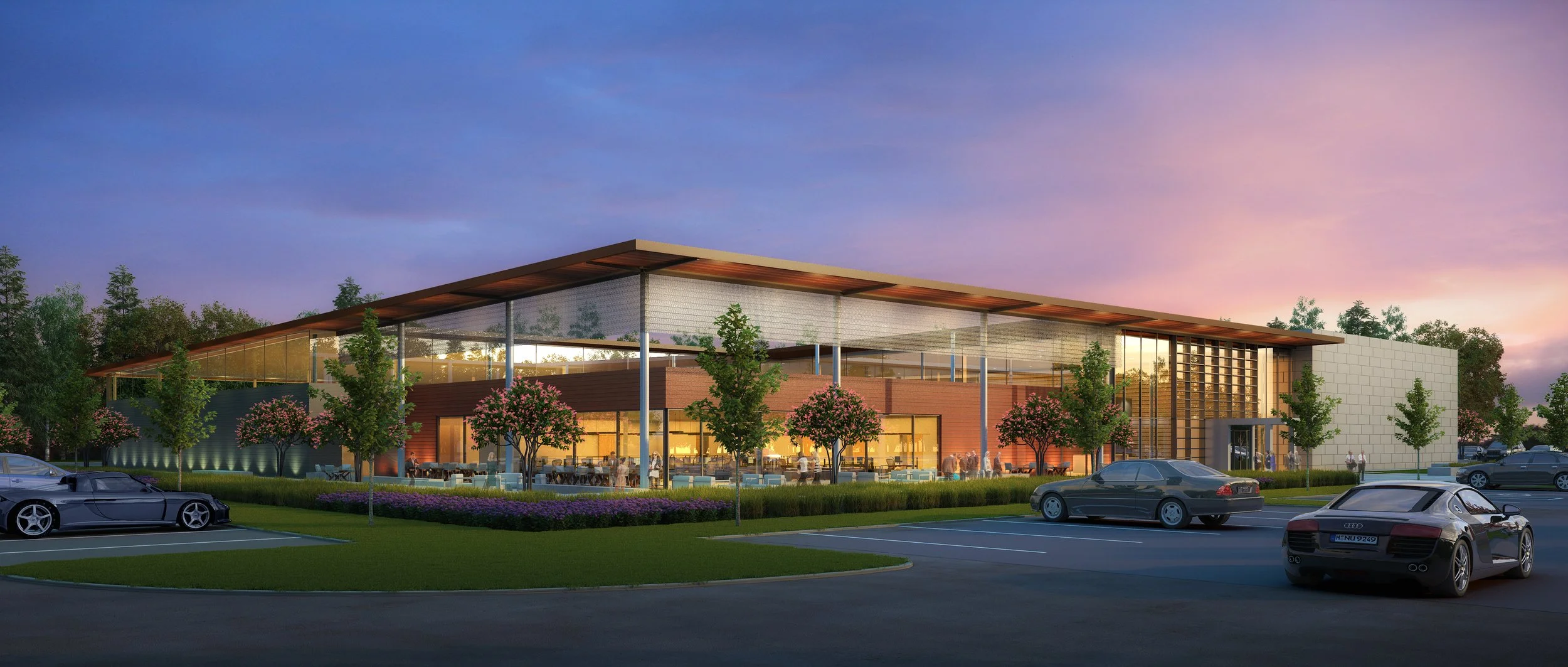 Modern architecture building with glass walls, surrounded by trees and parked cars at sunset.