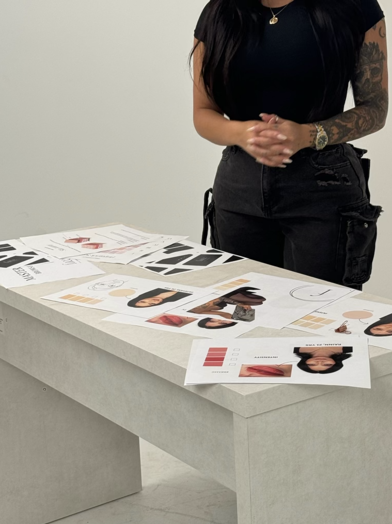 Person standing next to a table with printed design materials.