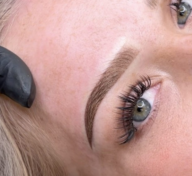 Close-up of a person's eye with dark eyelash extensions and well-groomed eyebrow.